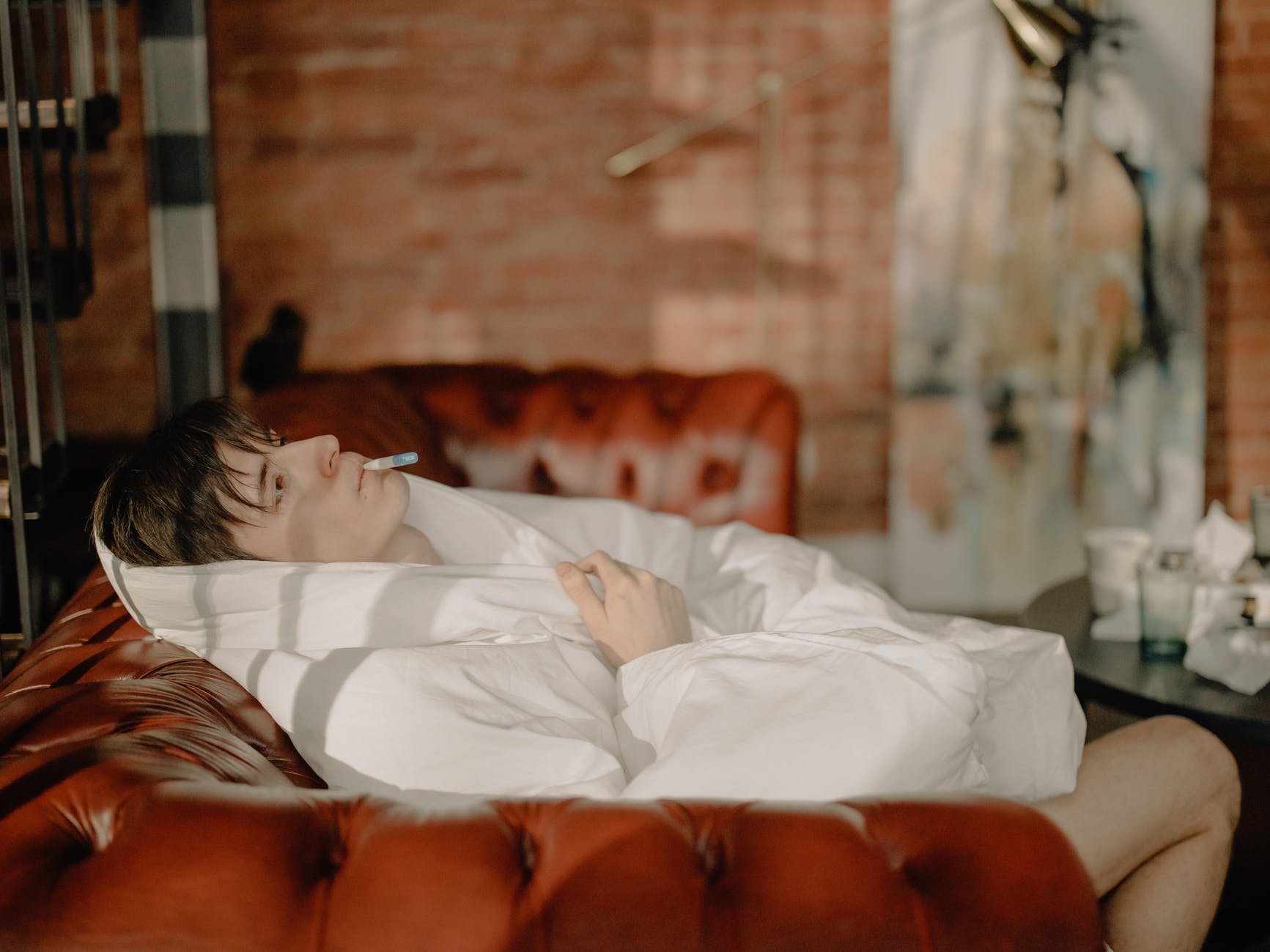 woman lying on bed covered with white blanket