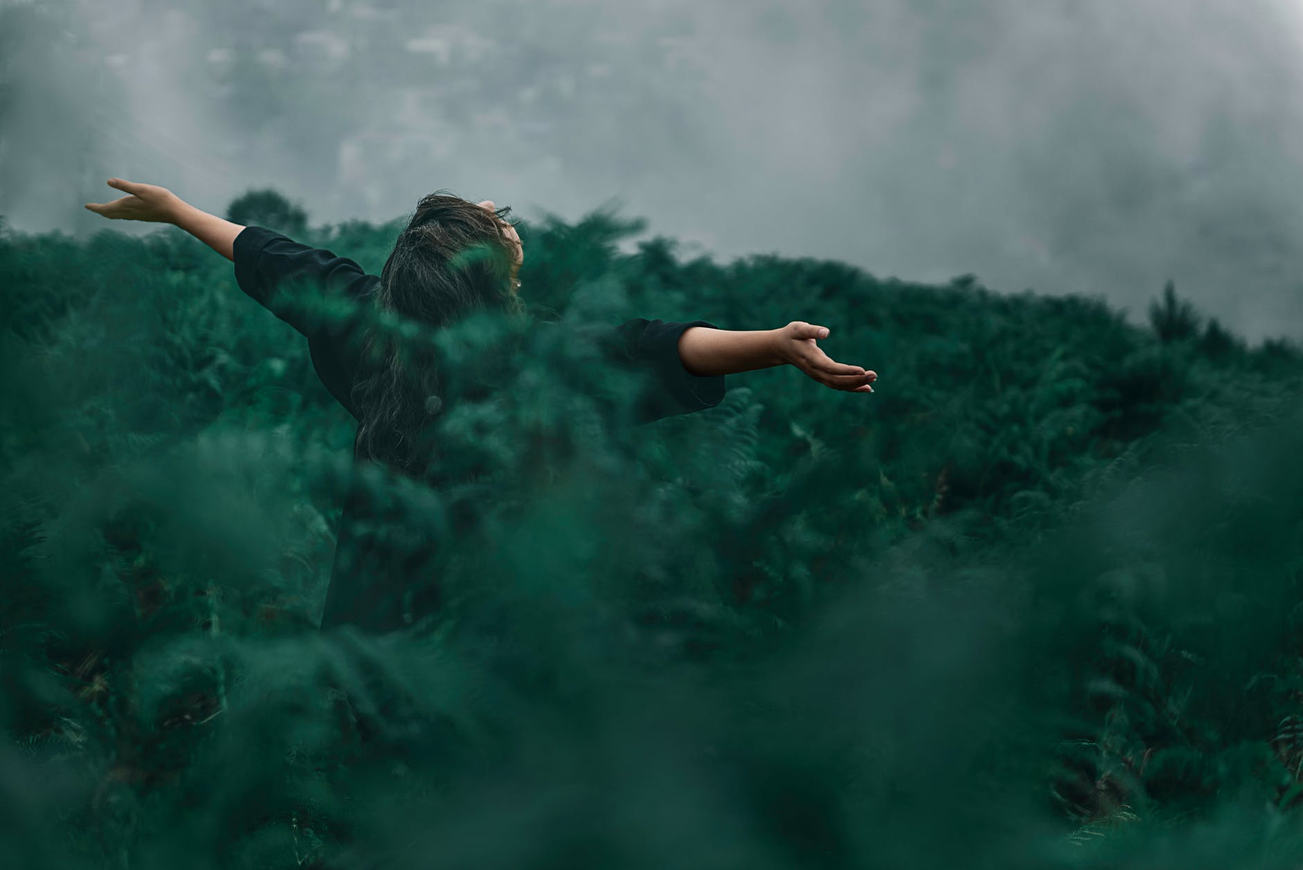 person standing on grass field while opening hands