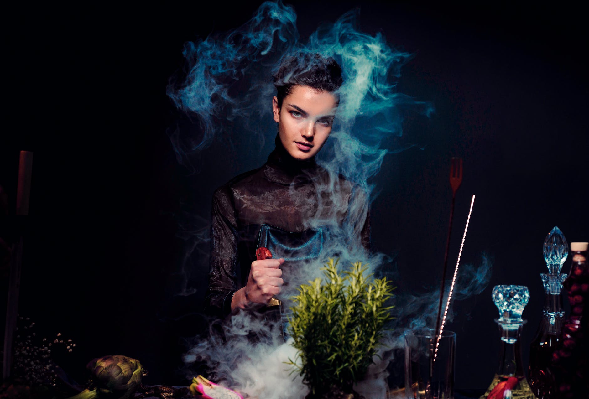 alluring young woman preparing potion against black background