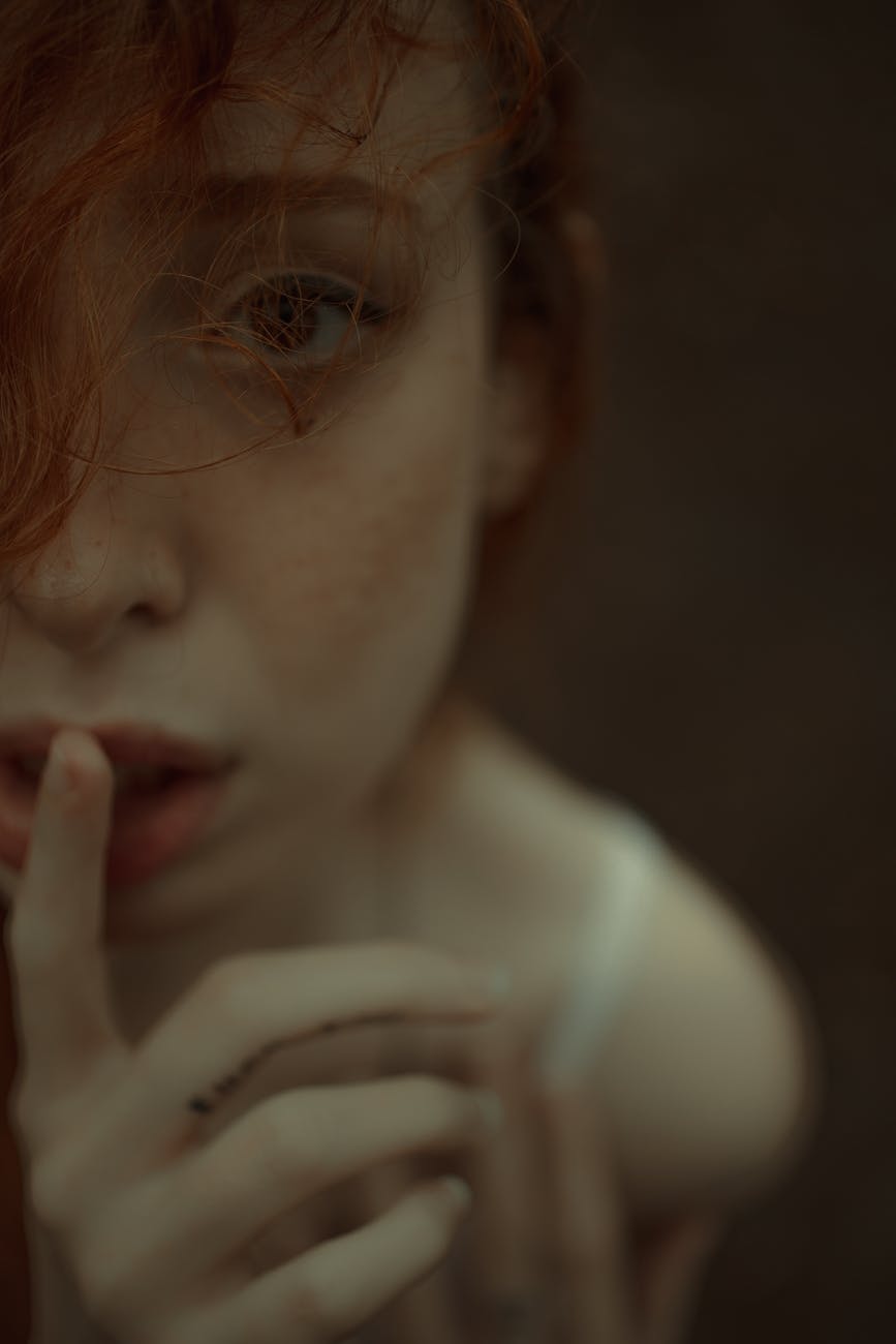 tender redhead woman with finger on lips
