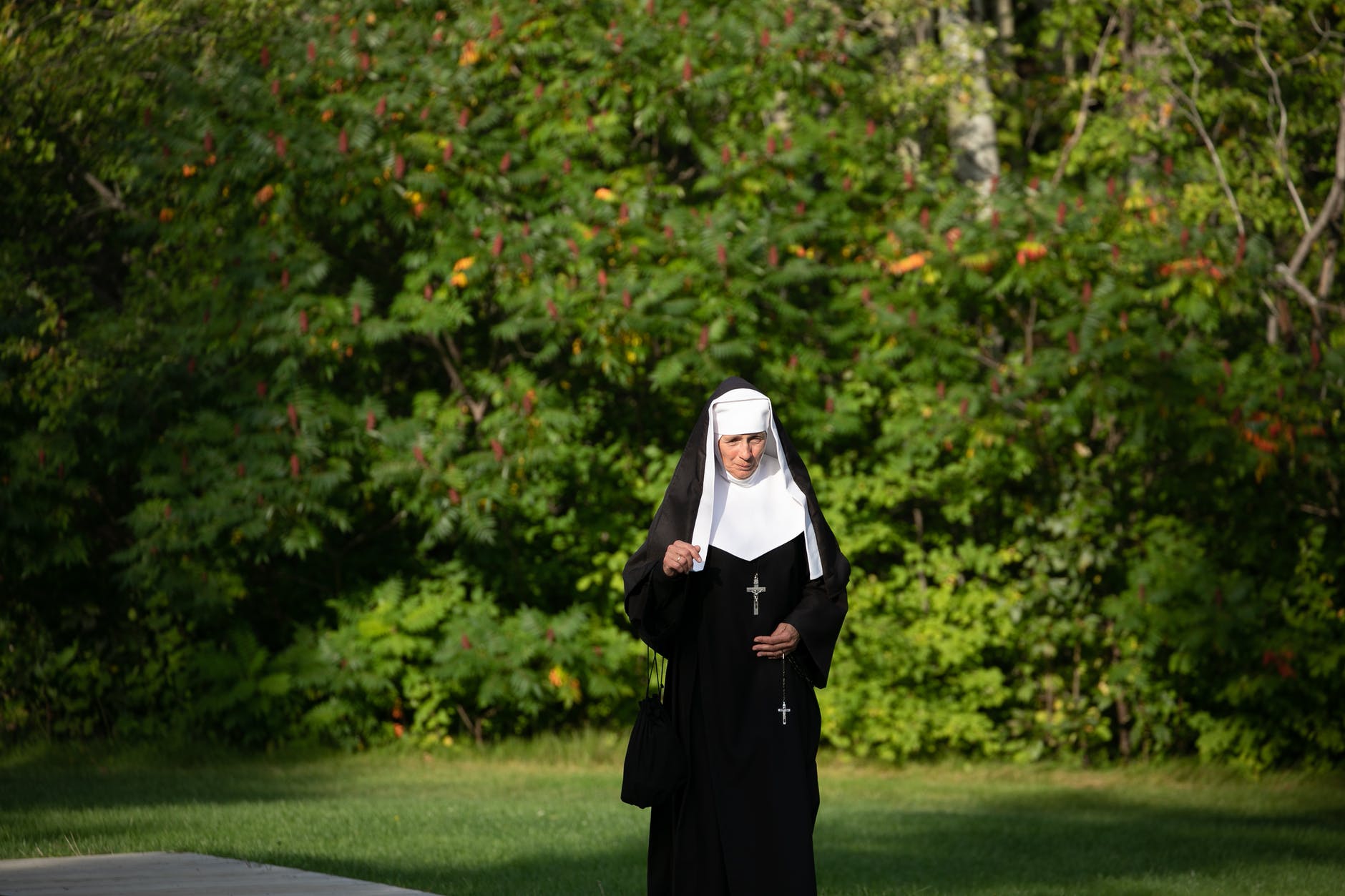 nun walking near trees