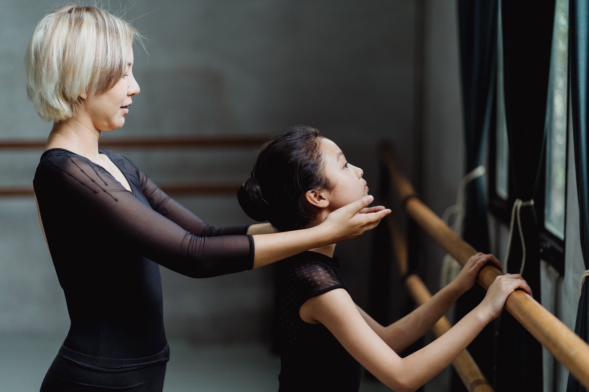 pupil doing exercises with ballet teacher in studio
