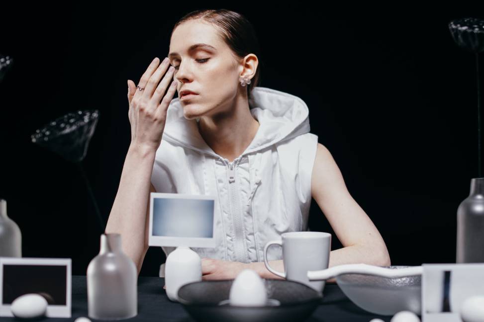 woman in white vest smelling her hand while her eyes are closed