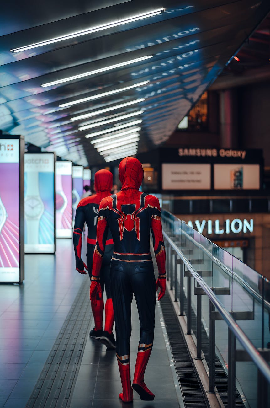 people wearing spider man adult costume walking on train station