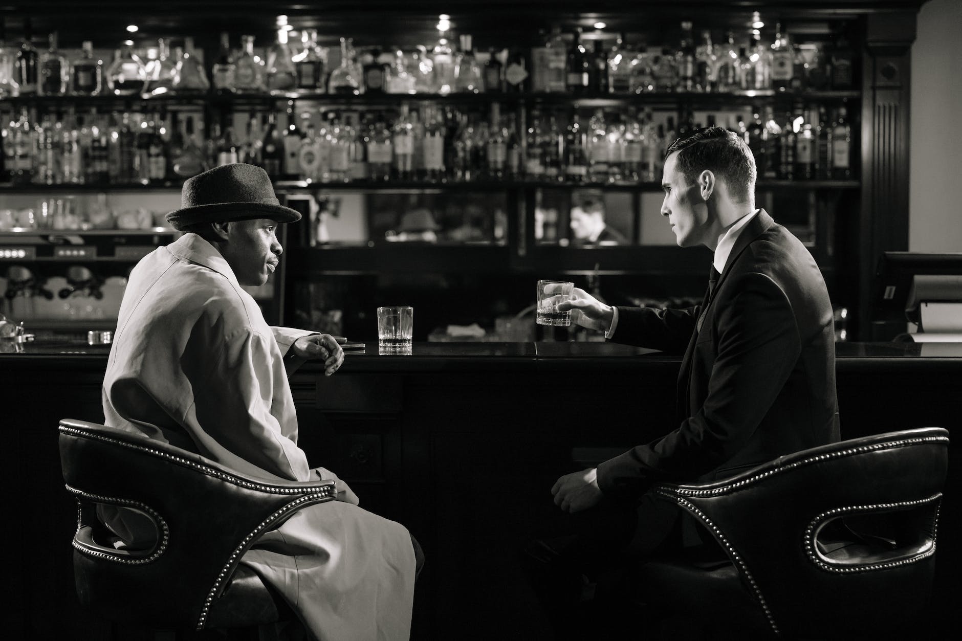 monochrome photo of men sitting in front of bar counter