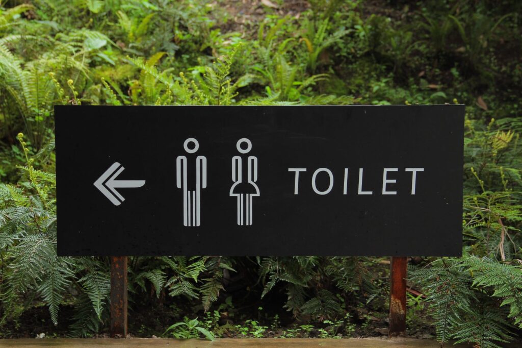 toilet signage beside green leaf