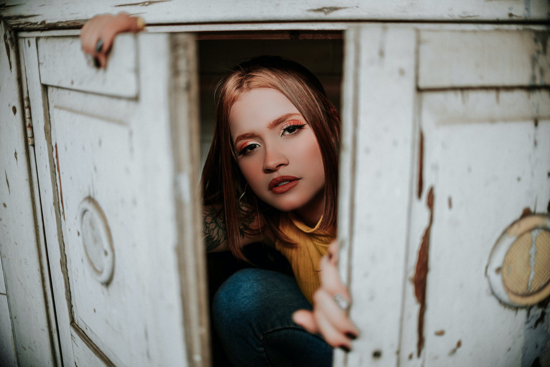 woman in blue denim jeans sitting on white wooden cabinet