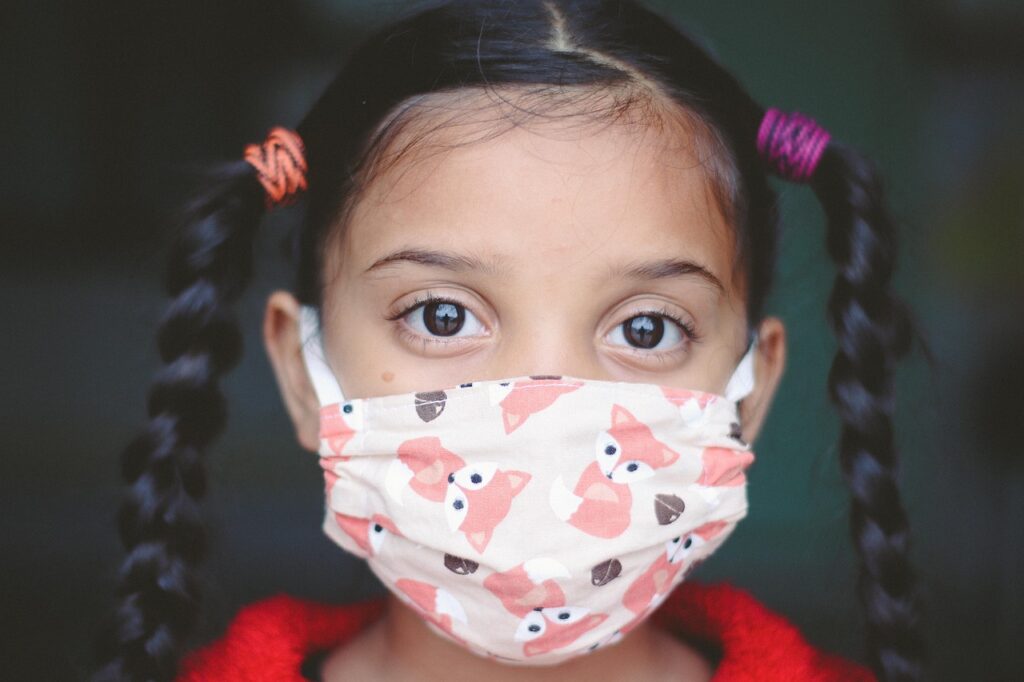 a little girl in a pink and white mask