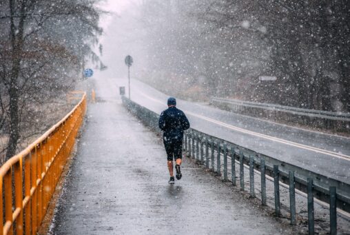Man running by a road in the rain